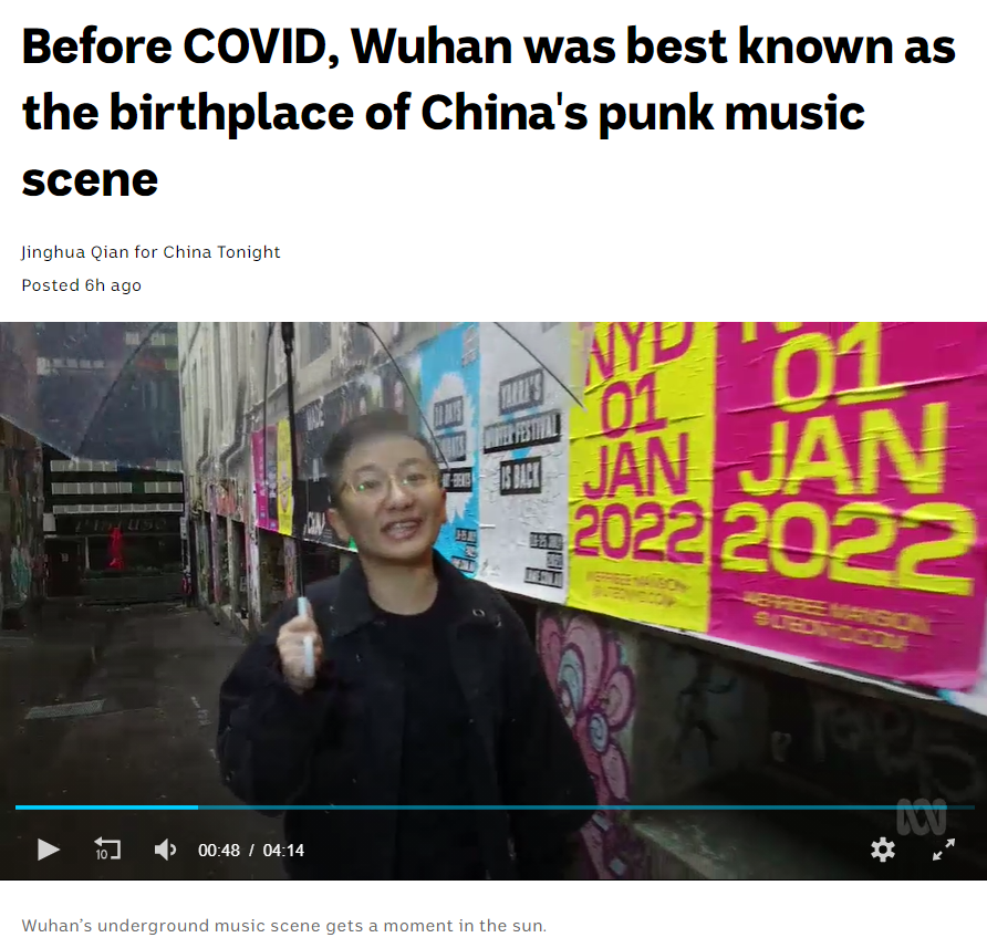 Screenshot of video with Jinghua standing in a laneway papered with gig posters. The headline says 'Before Covid, Wuhan was best known as the birthplace of China's punk music scene.'
